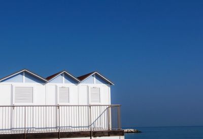 House on beach by sea against clear blue sky