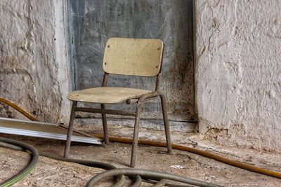 Empty chairs and table against wall in old building