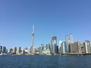 Sea by modern buildings against clear sky