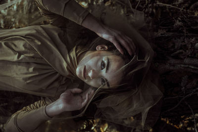 High angle portrait of beautiful young woman lying on field