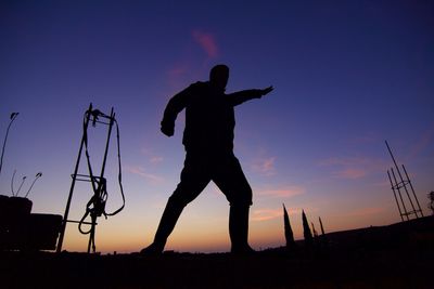 Silhouette man standing against sky during sunset