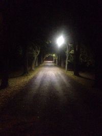 Empty road along illuminated street lights at night