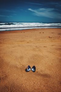 Sunglasses on beach against sky