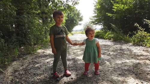 Siblings holding hands while standing amidst plants
