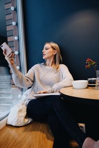 Woman using smart phone while sitting at cafe