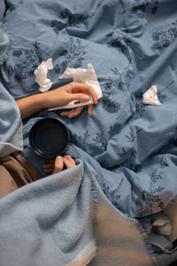 Unrecognizable young woman hold in hand thermometer and cup with hot beverage.