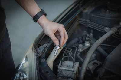 A young man holds a burnt out headlight bulb.