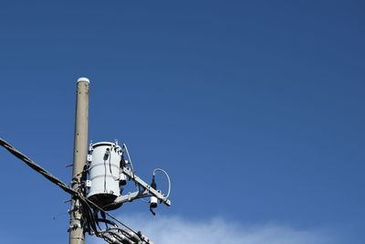 Low angle view of electlicy transformer against blue sky