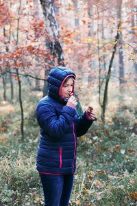 Woman wearing hood while standing in forest