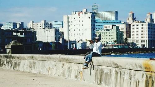 Man jumping in city against sky