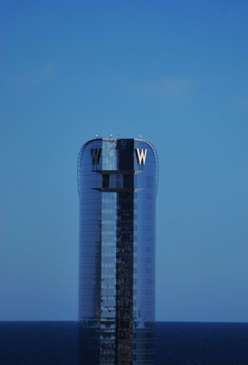 blue, clear sky, copy space, sea, built structure, protection, architecture, safety, lighthouse, water, building exterior, horizon over water, low angle view, security, tower, guidance, day, outdoors, no people, pole