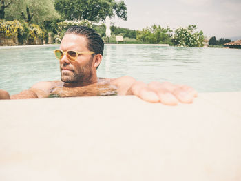 Shirtless man in swimming pool on sunny day