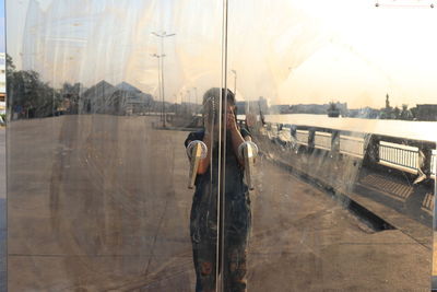 Reflection of woman photographing on glass door
