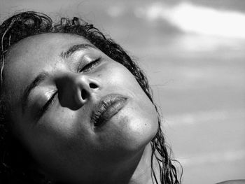 Close-up of young woman with eyes closed at beach during sunny day