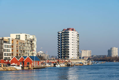 Buildings by sea against clear sky