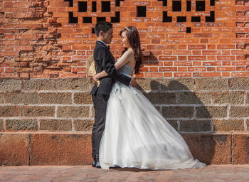 Rear view of couple kissing against brick wall