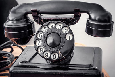 Close-up of black rotary phone against white background