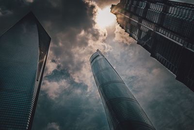 Low angle view of skyscrapers against cloudy sky