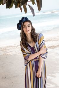 Young woman standing at beach against sky