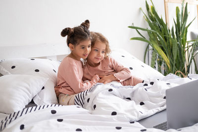 Cheerful girl looking at laptop whiles sitting on bed