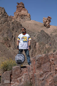 Low angle view of man standing on rock against sky