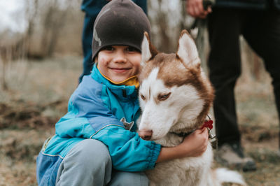 Kid and his friend husky siberian dog. portrait little child boy hugging cute white brown animal pet