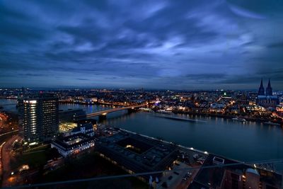 Illuminated cityscape against cloudy sky