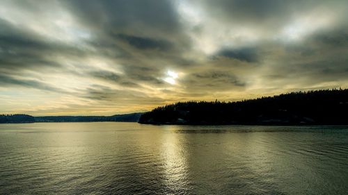 Scenic view of lake against dramatic sky during sunset