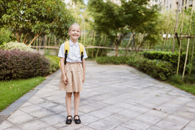 Portrait of young woman walking on footpath