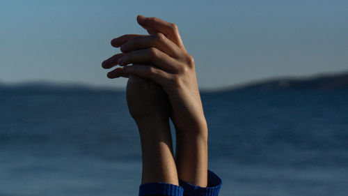 Midsection of woman hand on sea against sky