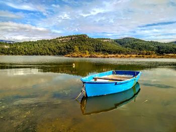 Boat moored in lake against sky