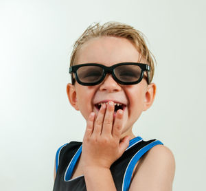 Cute boy playing with magnifying glass against white background