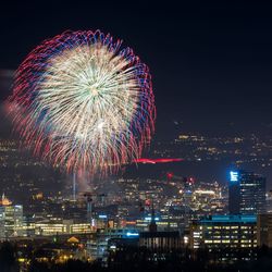 Firework display over illuminated buildings in city at night