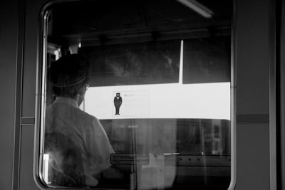 Rear view of man seen through glass window