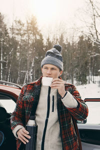 Portrait of mature man wearing hat against trees during winter