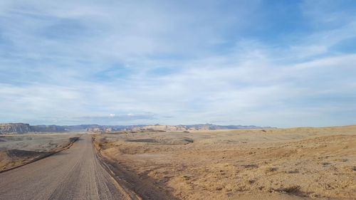 Road leading towards desert against sky