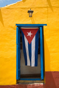 Multi colored flag on yellow wall of building