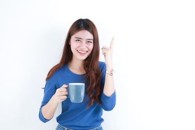 Young woman drinking coffee cup against white background