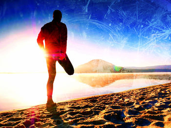 Rear view of man on beach against bright sun