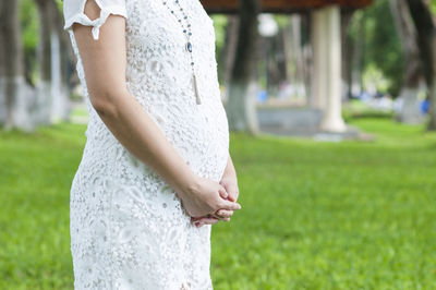 Midsection of pregnant woman standing in park
