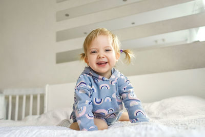 Portrait of smiling boy on bed at home