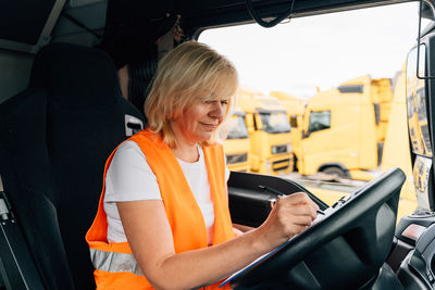 Woman writing while sitting in truck