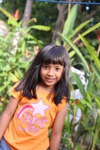 Portrait of young woman standing amidst plants