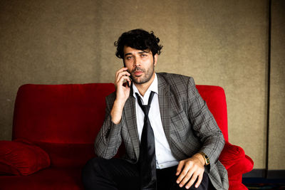 Young man looking away while sitting on sofa