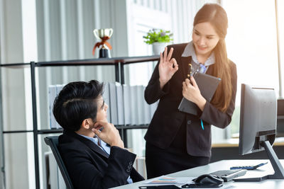 Young woman using mobile phone while sitting in office