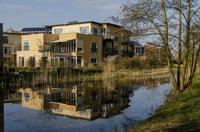 Wooden housing block in lanxmeer neighbourhood reflecting in the adjacent pond in the golden hour