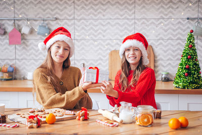 Portrait of girls holding gift box sitting at home
