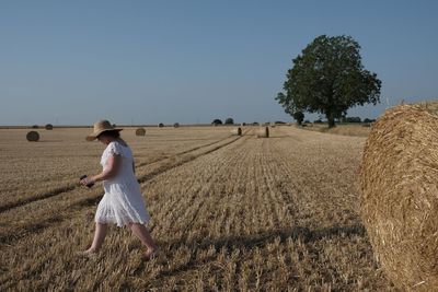 Rear view of woman walking on field against sky