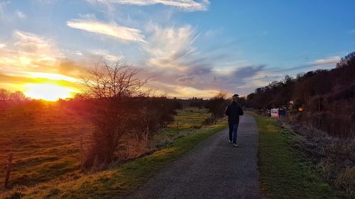 Rear view of silhouette man walking on road against sky