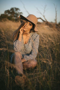 Young woman wearing hat sitting on field